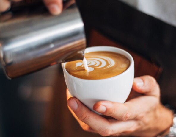 Stock photo - Pouring steamed milk into coffee cup