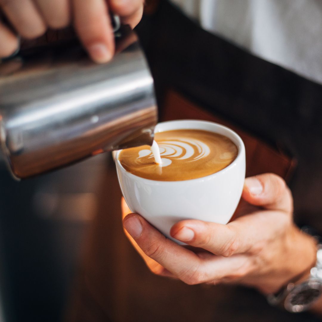 Stock photo - Pouring steamed milk into coffee cup